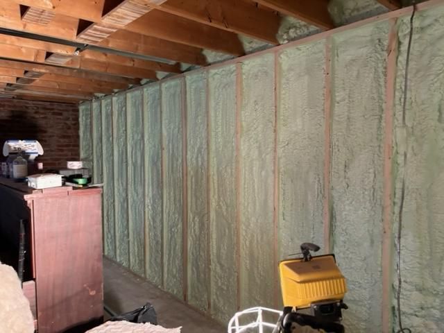 Construction de murs avec isolation en mousse projetée dans un espace intérieur non fini.