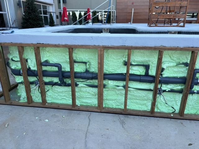 Construction de la piscine : structure en bois avec tuyaux et isolation. Mousse verte pour le remplissage des espaces.