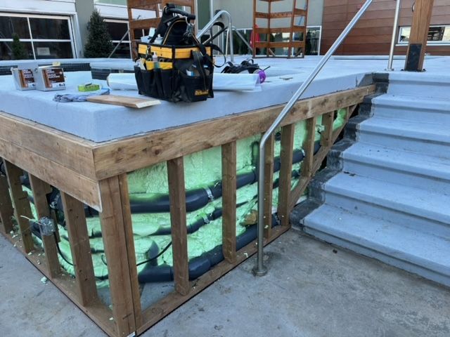 Terrasse en bois en construction, marches, isolation et boîte à outils visibles.