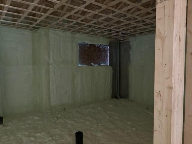 Intérieur du sous-sol avec isolation en mousse pulvérisée sur les murs et le plafond, les fenêtres et les tuyaux.
