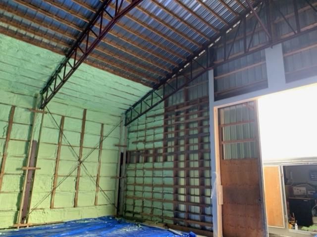 Intérieur d'un entrepôt avec isolation en mousse pulvérisée verte sur les murs et le plafond.