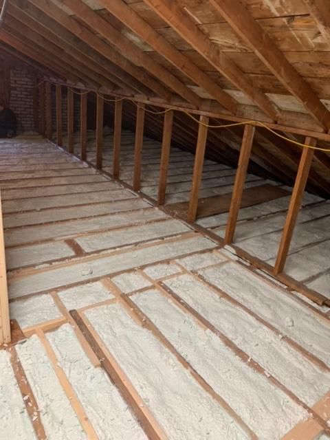 Intérieur loft avec poutres en bois et isolation remplissant les espaces entre les solives.