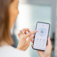 A person uses a smartphone app with a digital padlock icon to unlock a smart home device.