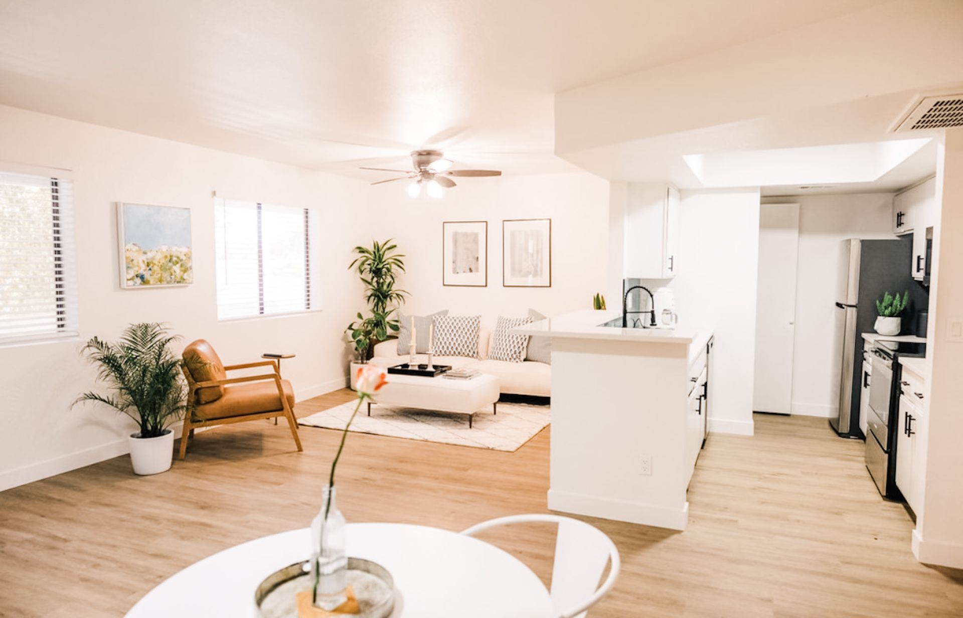 Bright, airy living space with open kitchen. White walls, light wood floors, modern furniture.