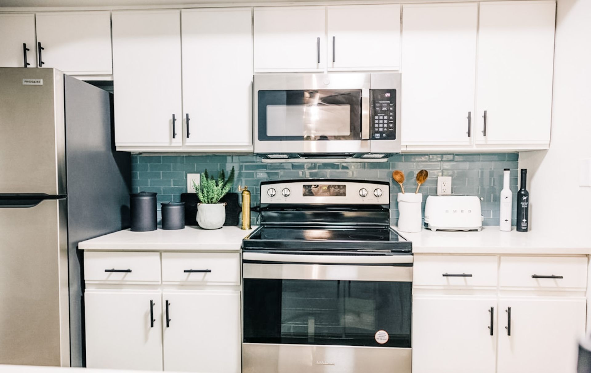 White kitchen with stainless steel appliances and blue backsplash.