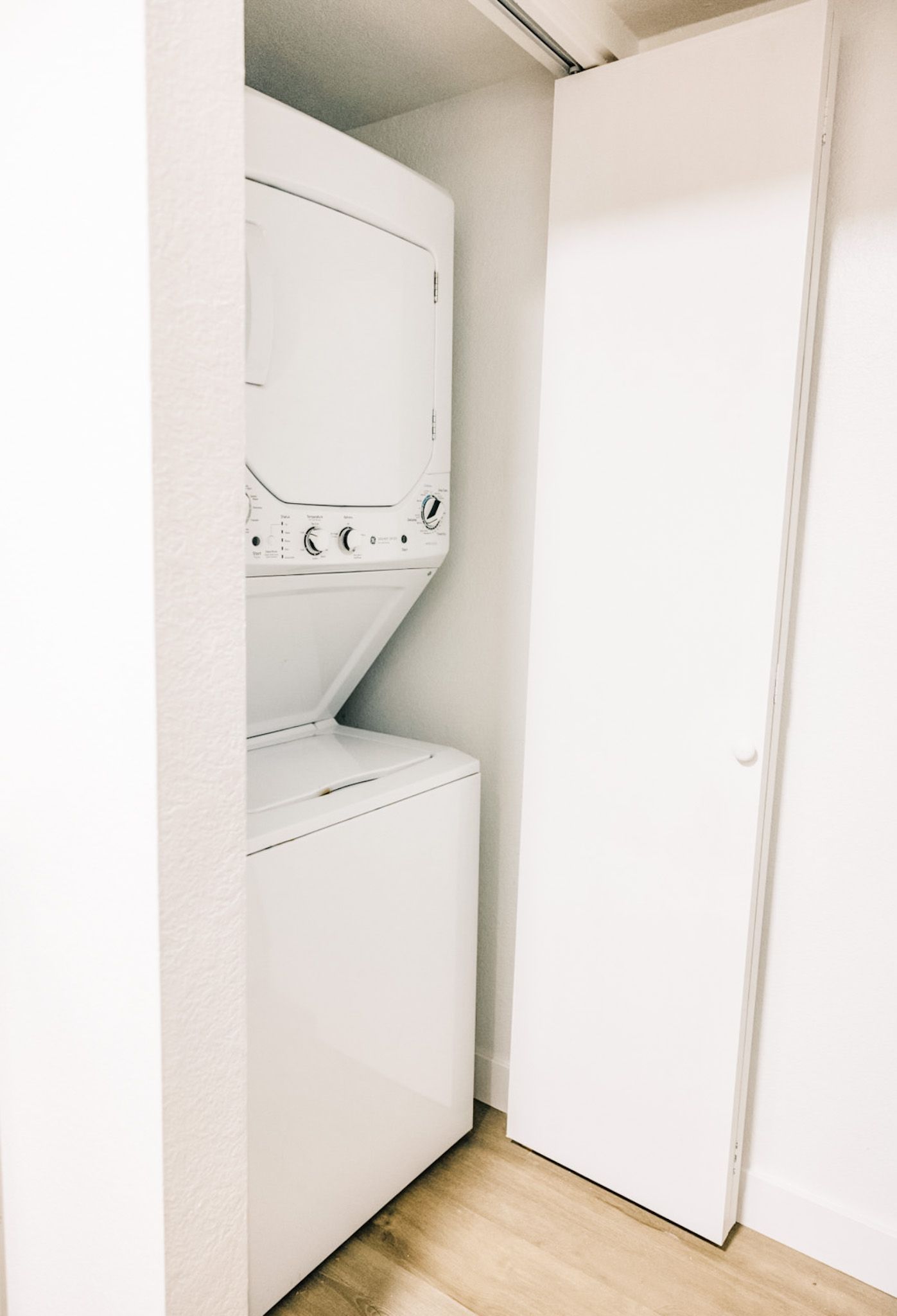 Stackable white washer and dryer in a closet with a closed white door.