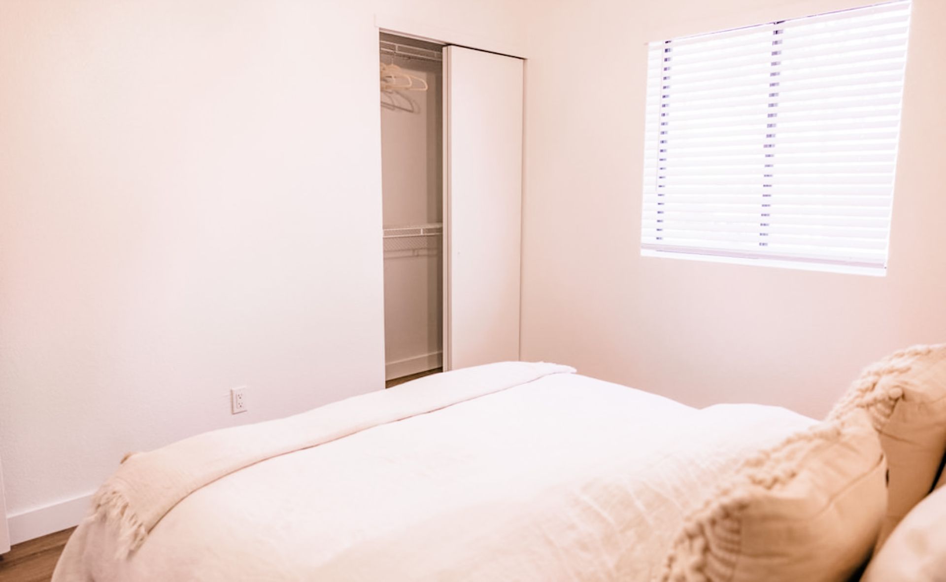 Bedroom with bed, closet, and window with blinds.