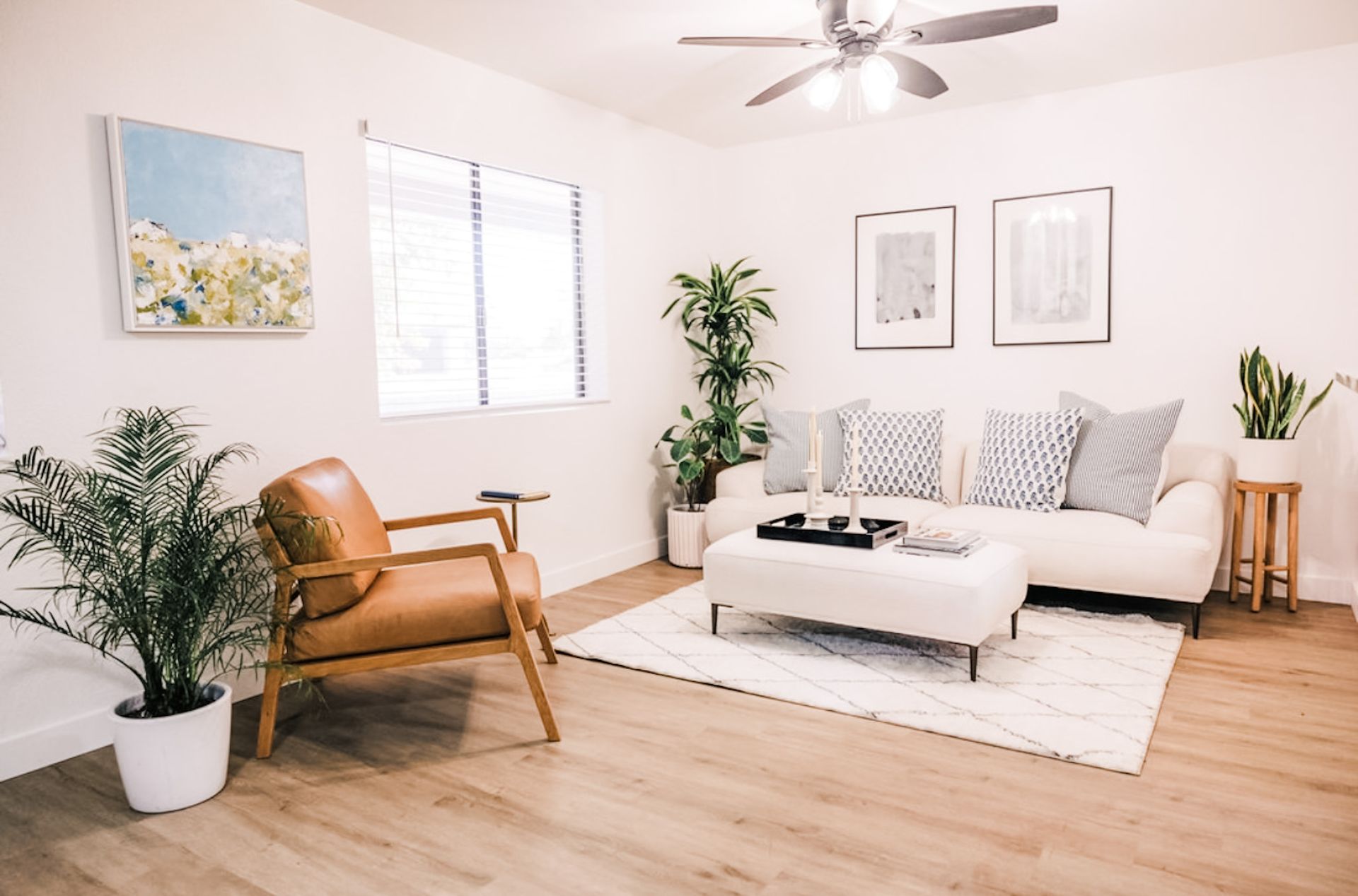 Living room with a white couch, plants, and a brown leather chair.