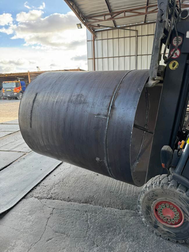 Se levanta un tubo metálico de gran tamaño mediante una carretilla elevadora.