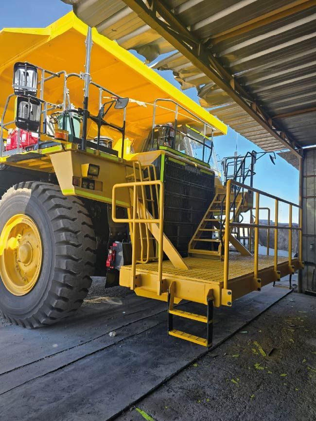 Un gran camión amarillo está estacionado bajo un techo.