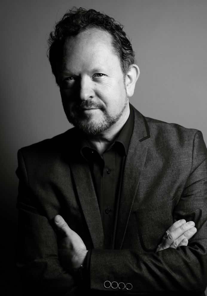 Simon Frith in a suit, arms crossed, looking at the camera. Black and white portrait with soft lighting.