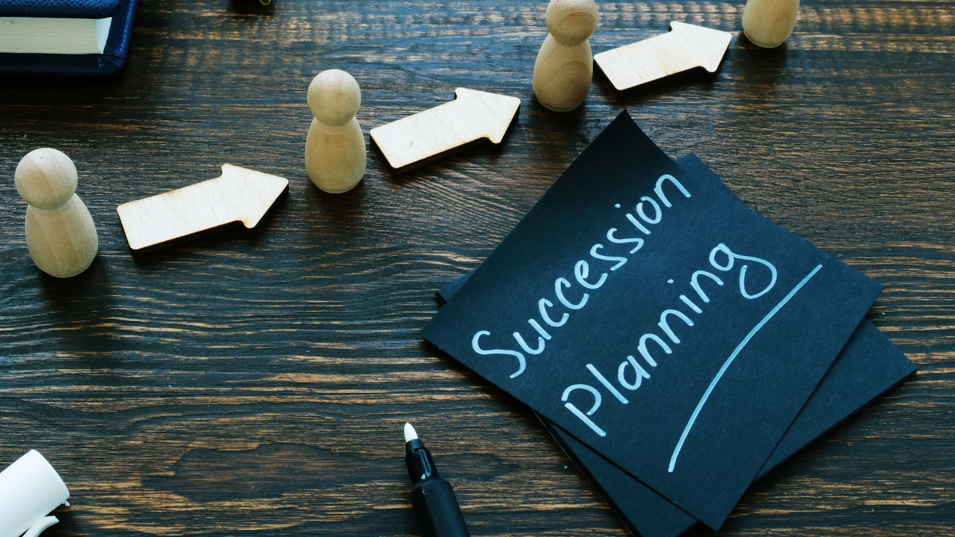 A note on a wooden table that says succession planning