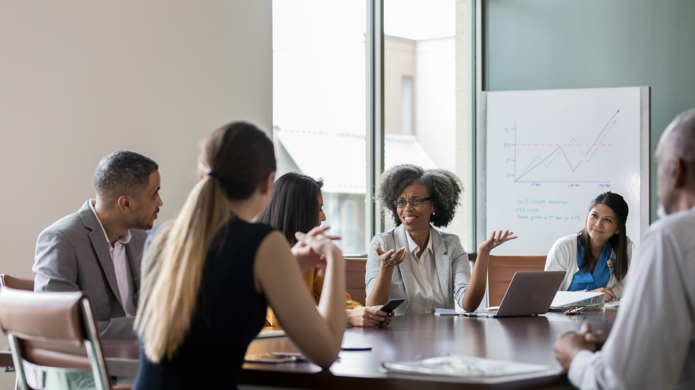 A group of people are sitting around a table having a meeting about nonprofit accounting