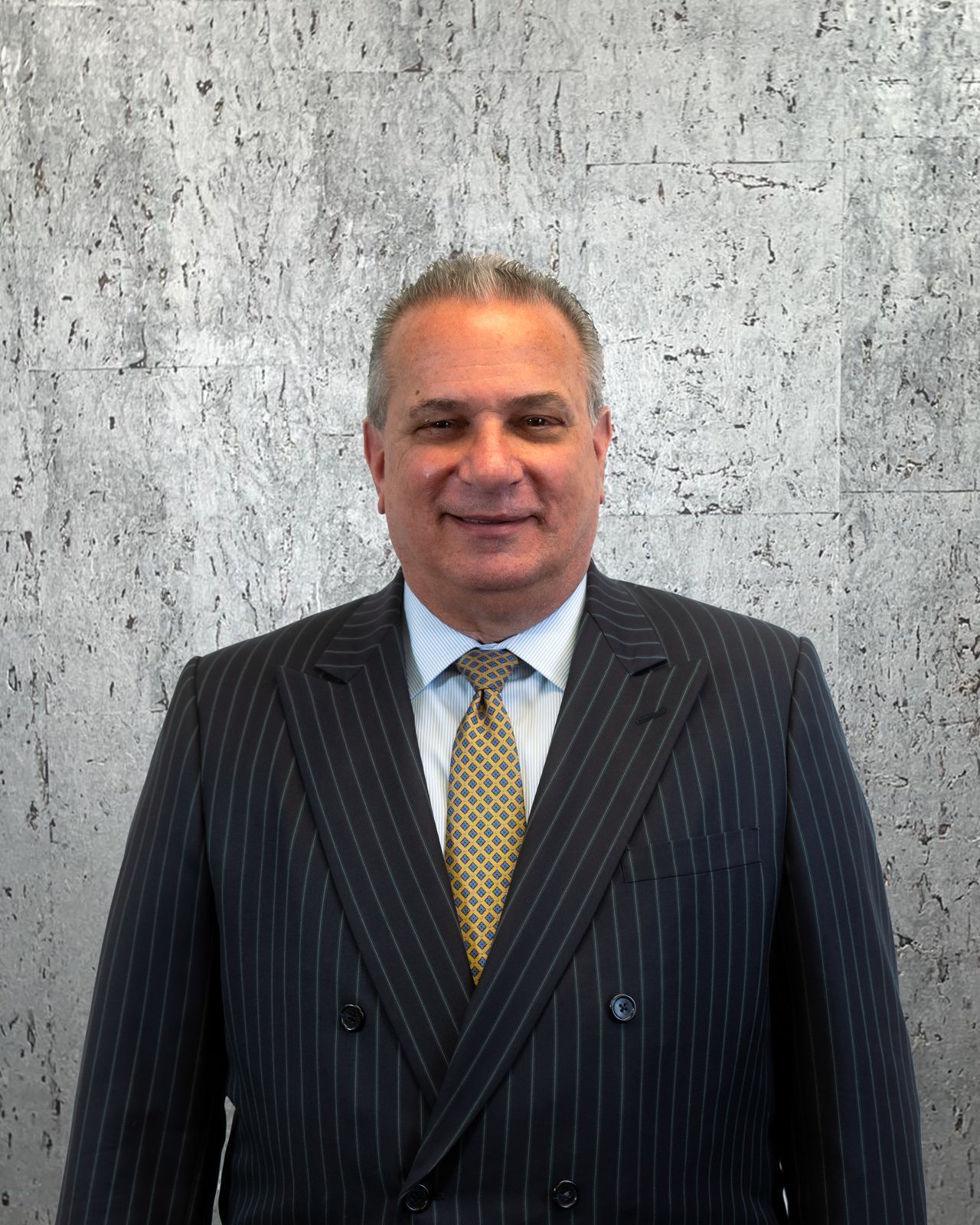 A man in a suit and tie is standing in front of a concrete wall.
