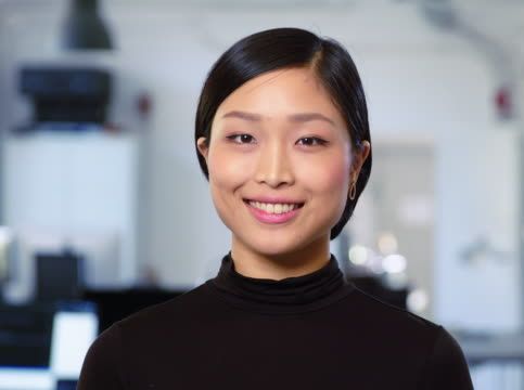 A woman in a black turtleneck is smiling for the camera.