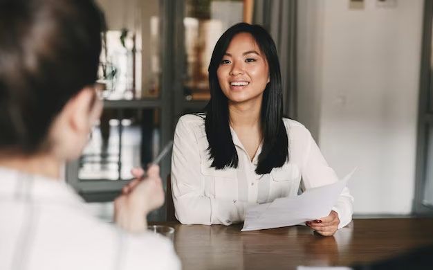 A woman is sitting at a table talking to another woman.