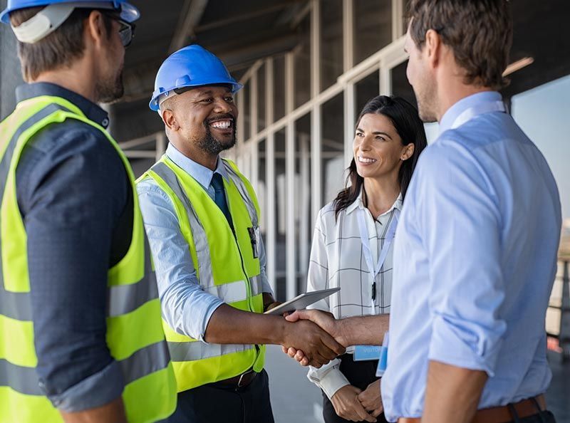 A group of construction workers are shaking hands with a businessman.