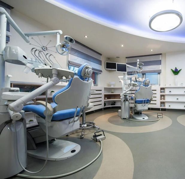 A dental office with blue chairs and white equipment