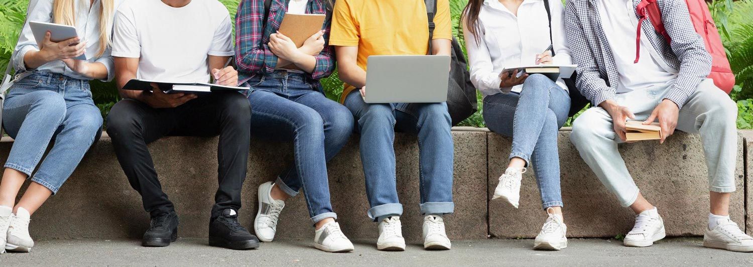 A group of young people are sitting on a stone wall.