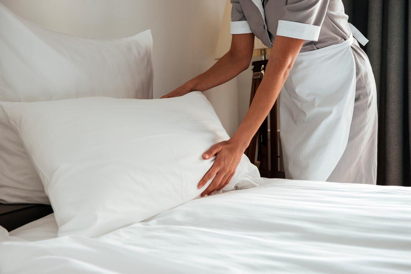 A maid is making a bed in a hotel room.
