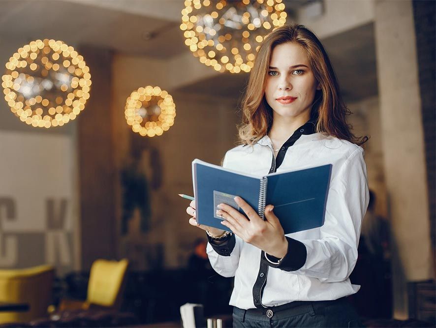 A woman is holding a book in her hands in a restaurant.