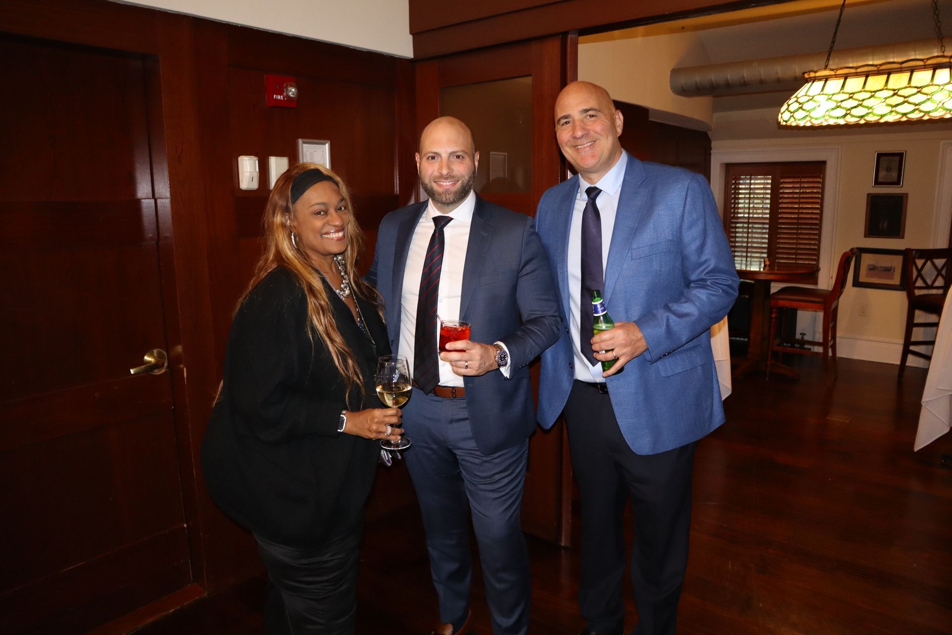 Three people in suits and ties are standing next to each other in a room.