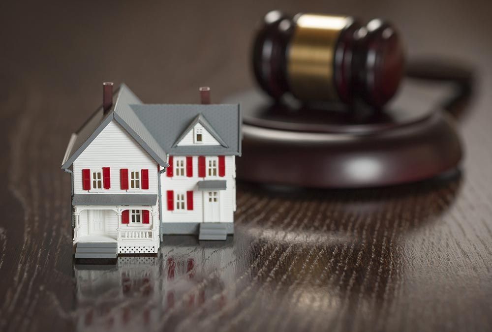 A model house sits on a wooden table next to a judge 's gavel.