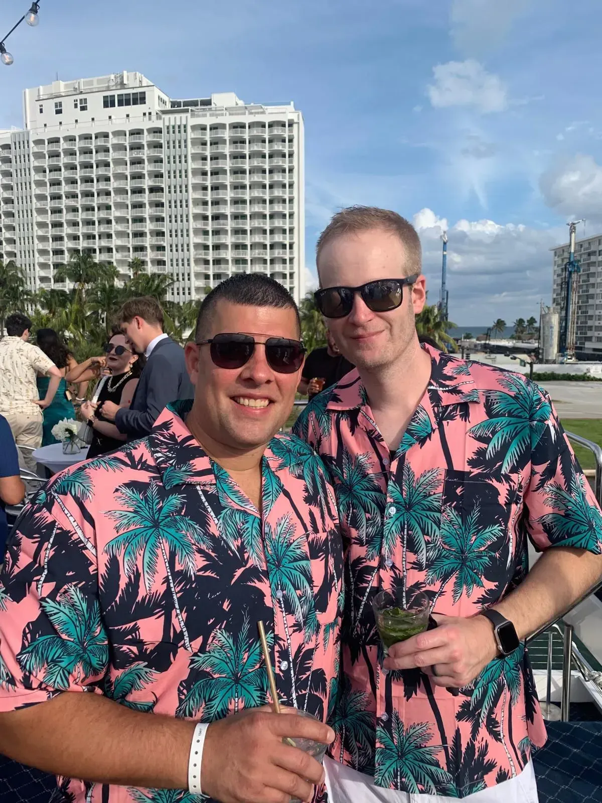 Two men wearing hawaiian shirts and sunglasses are posing for a picture.