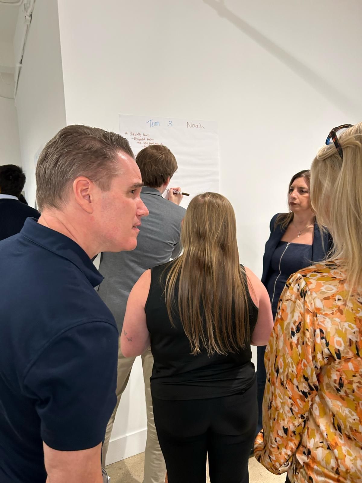 A group of people are standing in a room talking to each other.