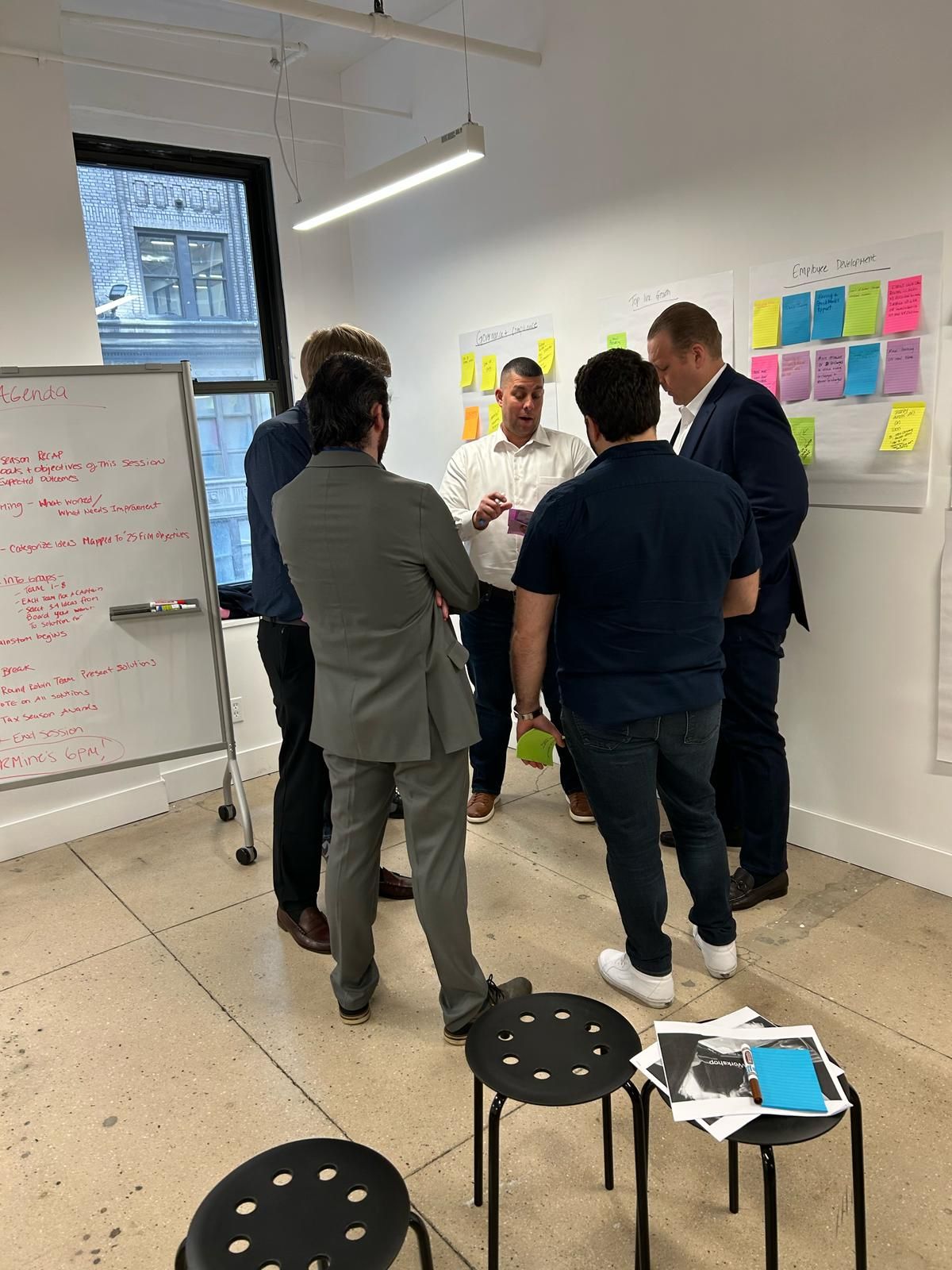 A group of men are standing in a room talking to each other.