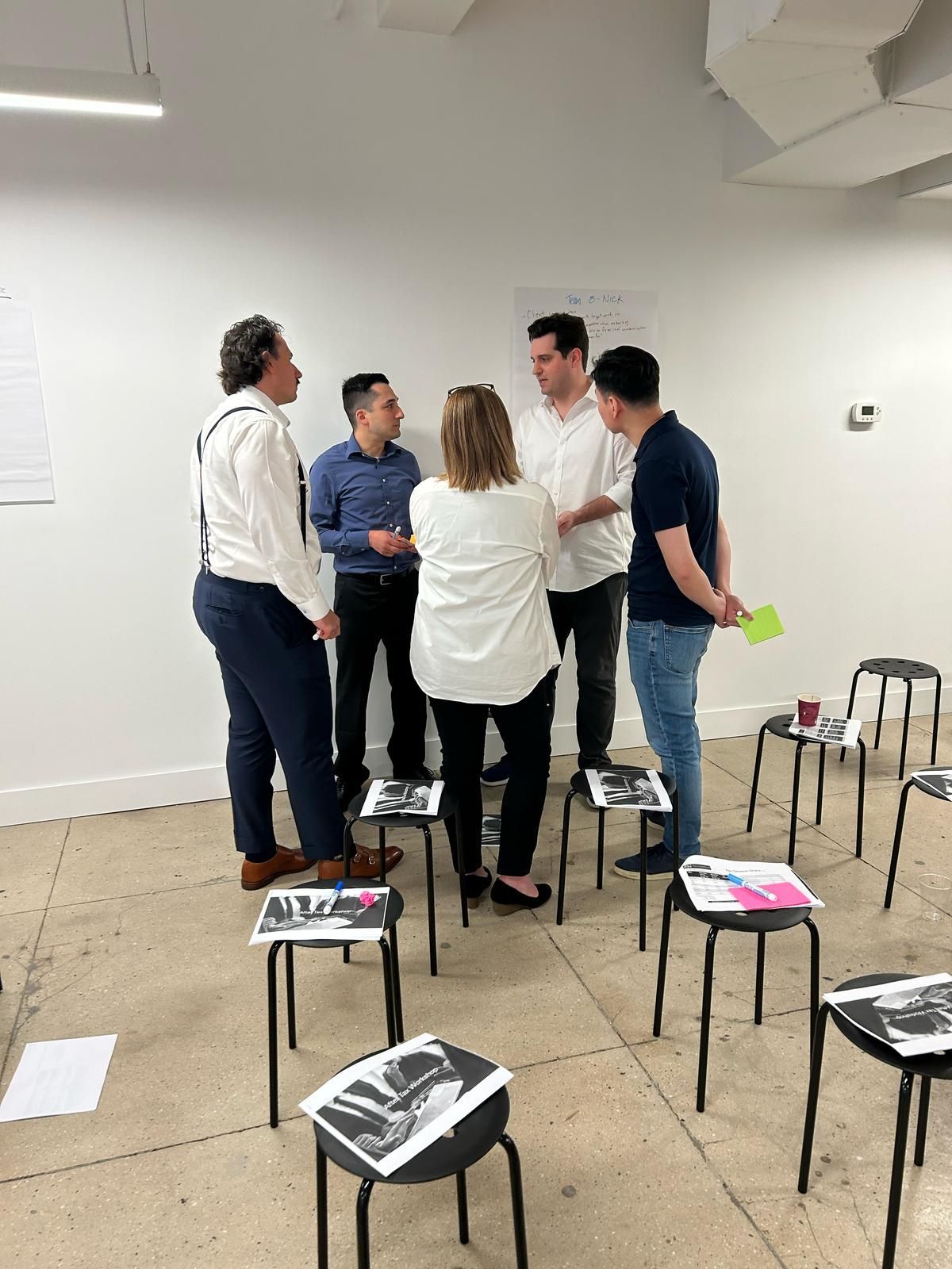 A group of people are standing around stools in a room.