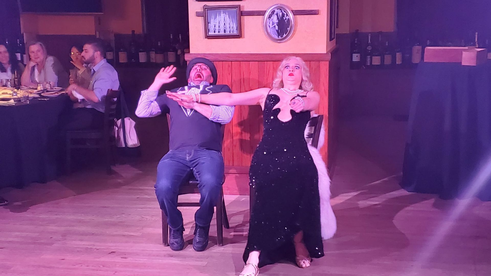 A man and a woman are dancing on a stage in a restaurant.