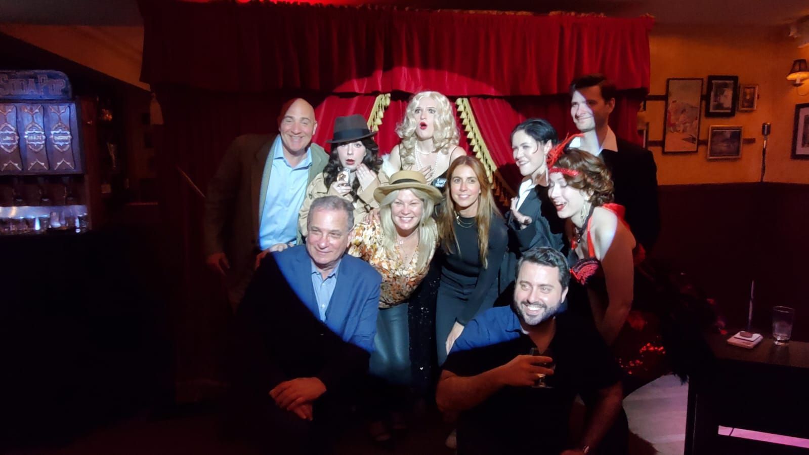 A group of people are posing for a picture in front of a red curtain.