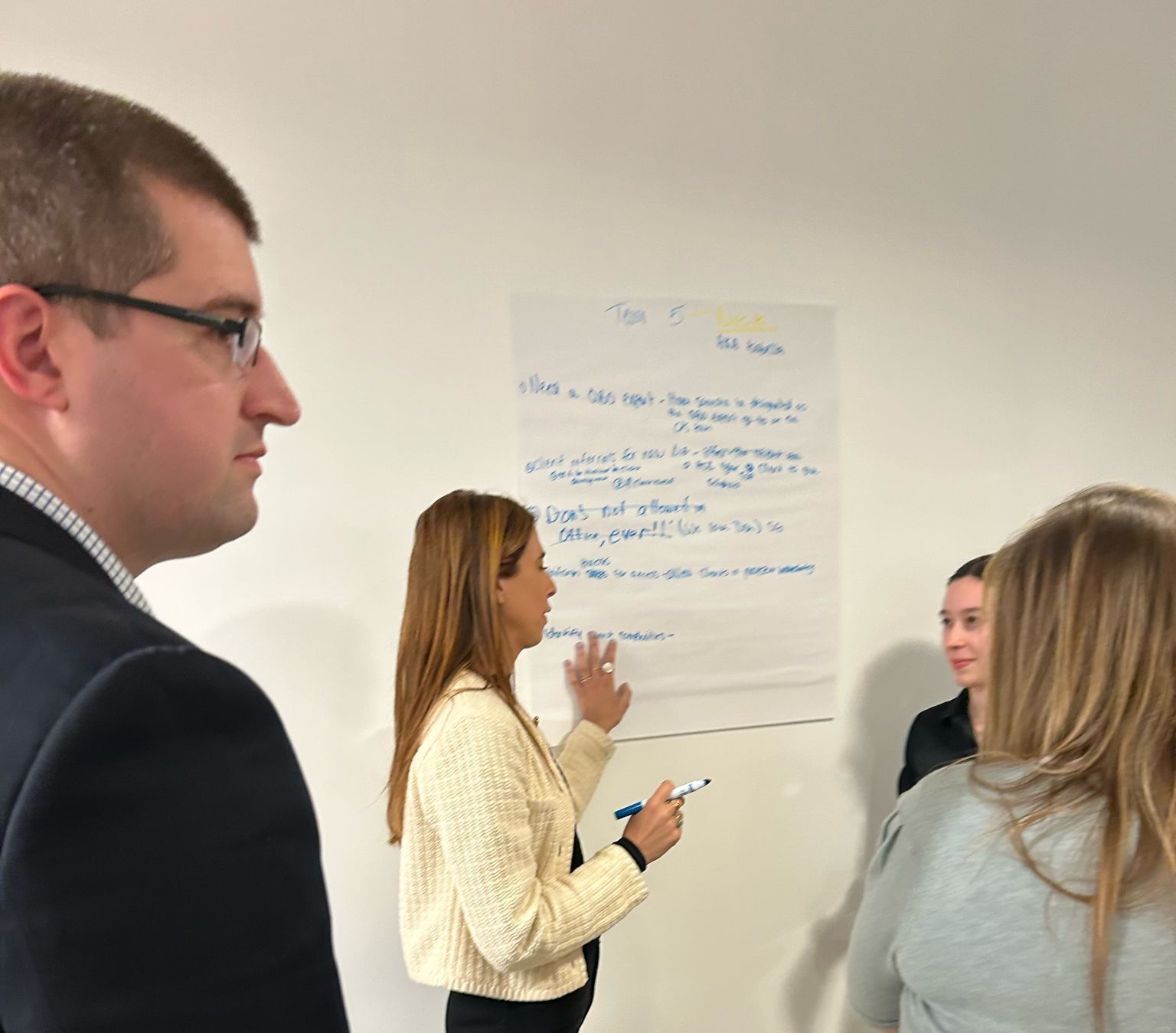 A group of people are standing around a white board