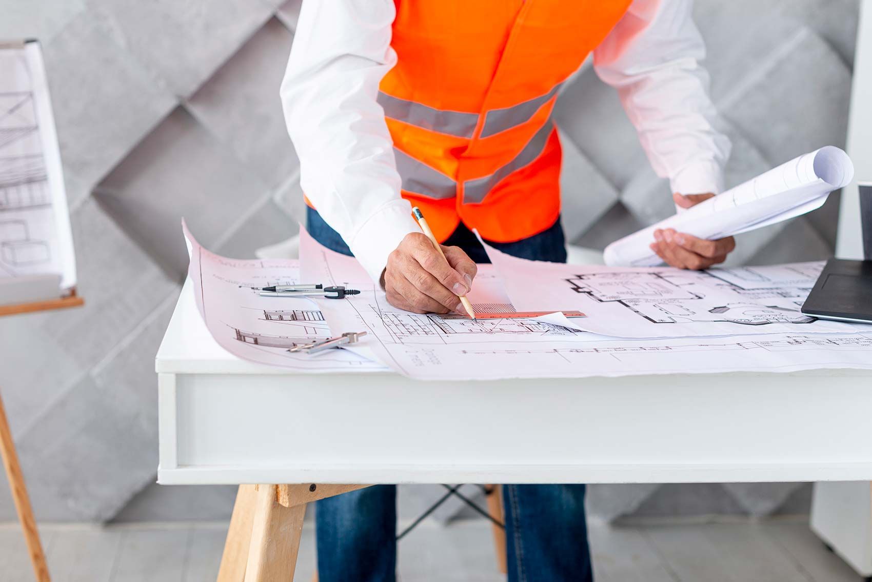 A man in an orange vest is writing on a piece of paper.