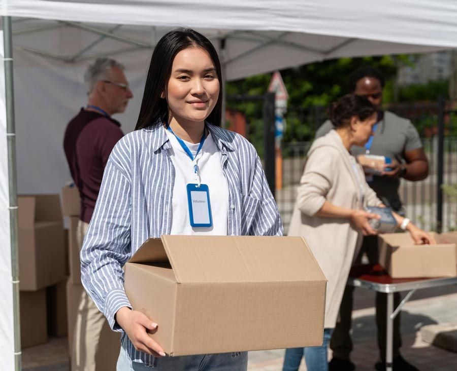 A woman is holding a cardboard box in front of a tent.