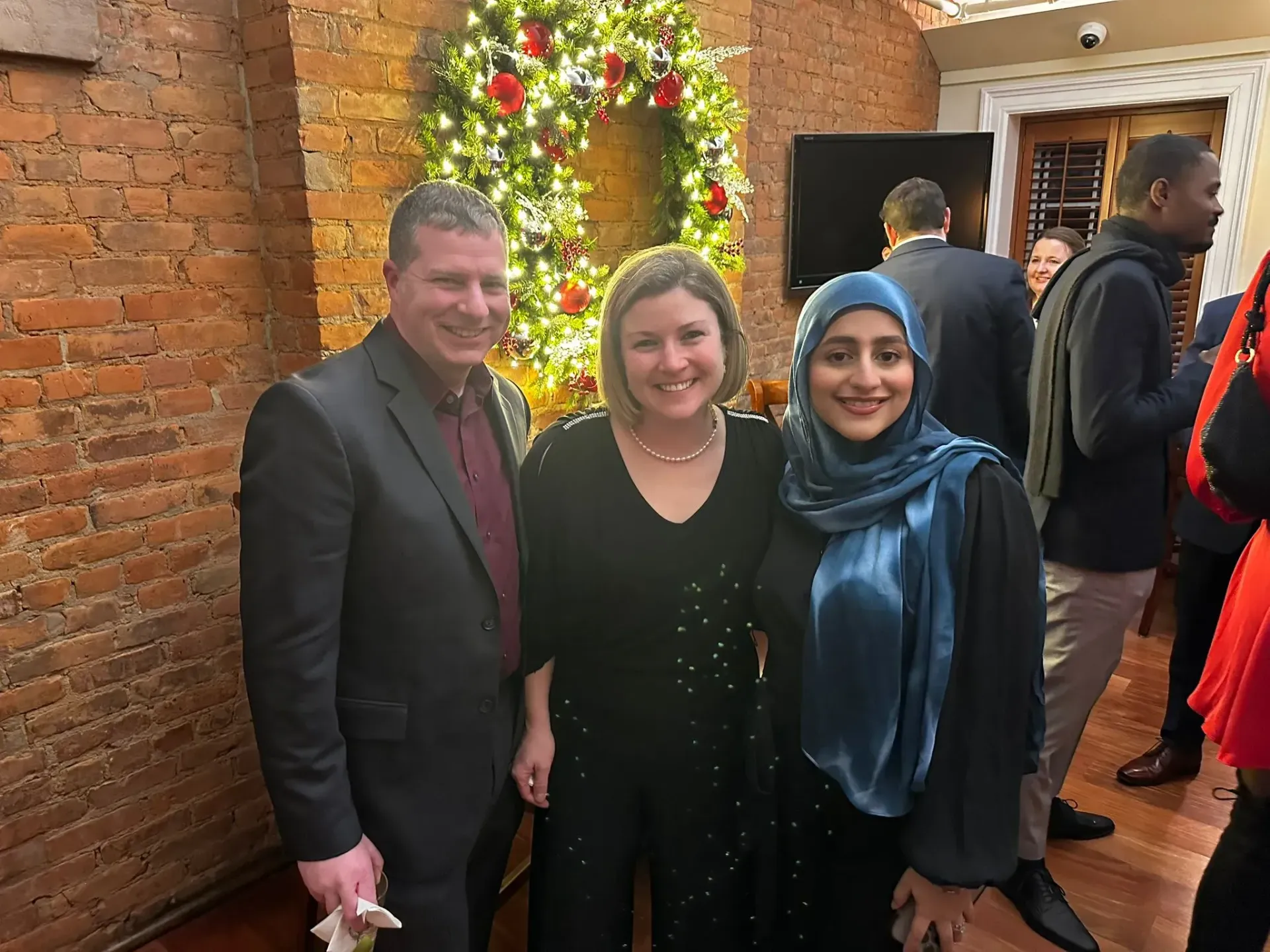 A group of people are posing for a picture in front of a christmas wreath.