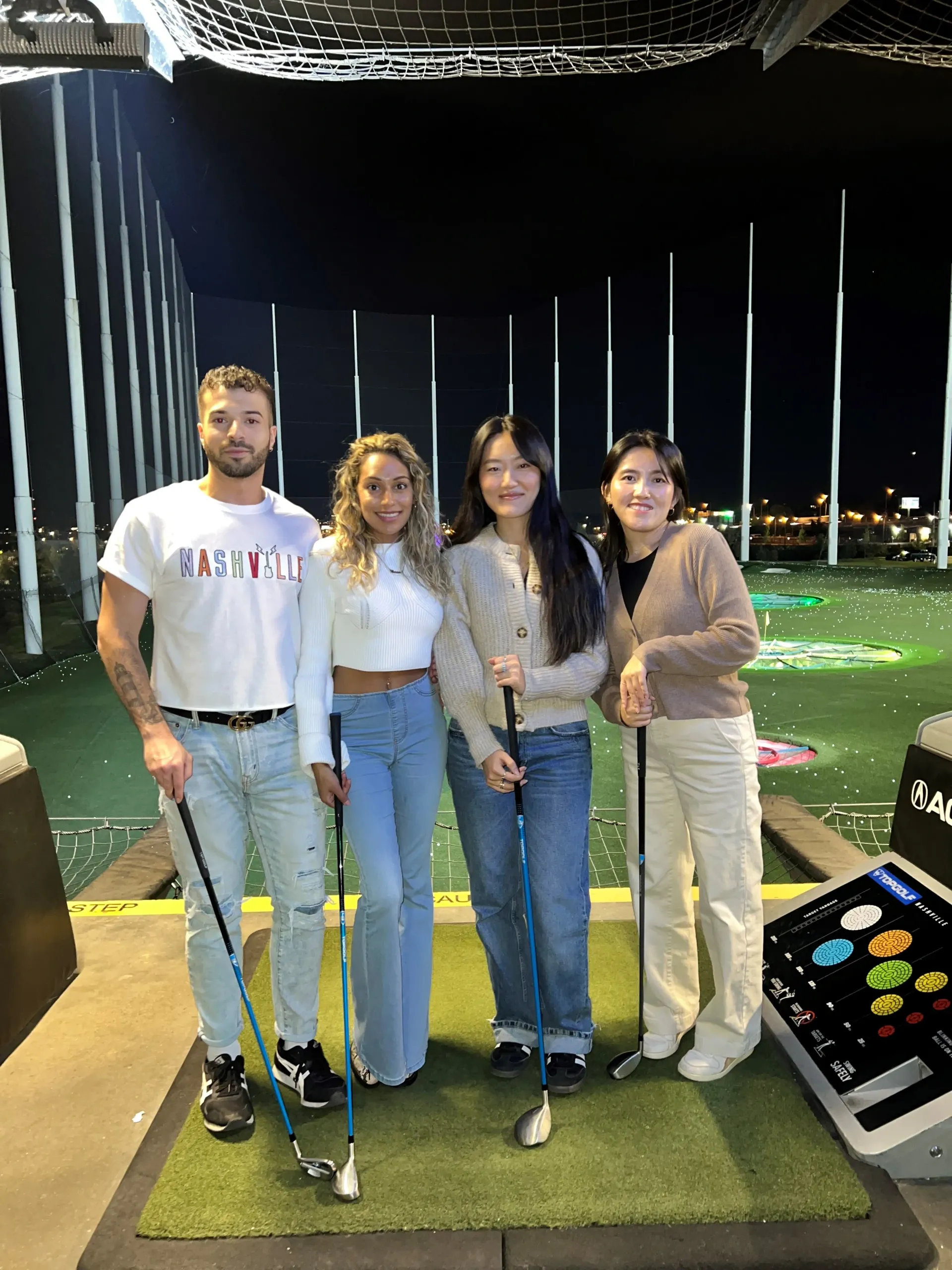 A group of people standing next to each other on a golf course holding golf clubs.