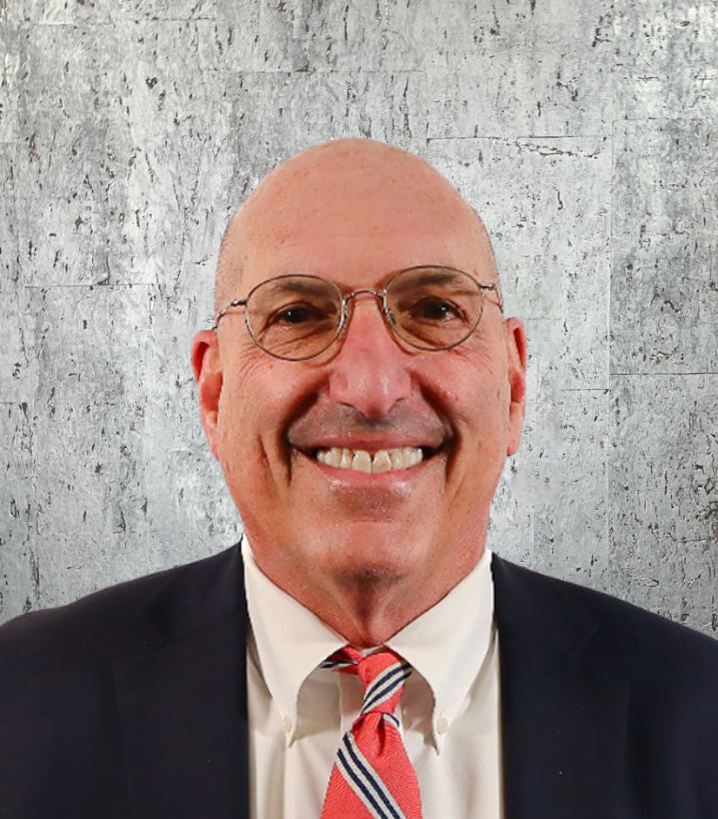 A bald man wearing glasses and a suit and tie is smiling.