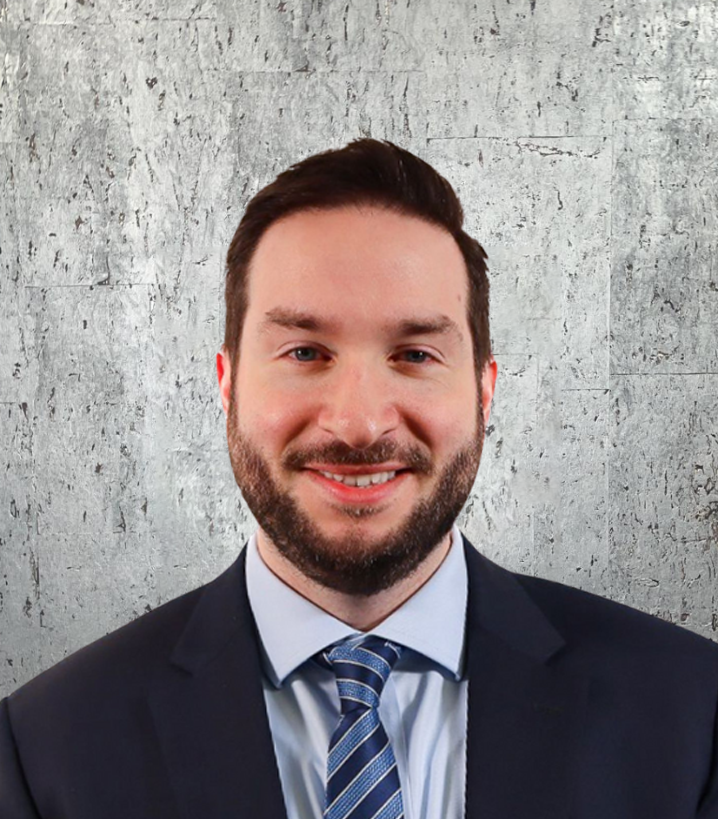 A man with a beard is wearing a suit and tie and smiling.
