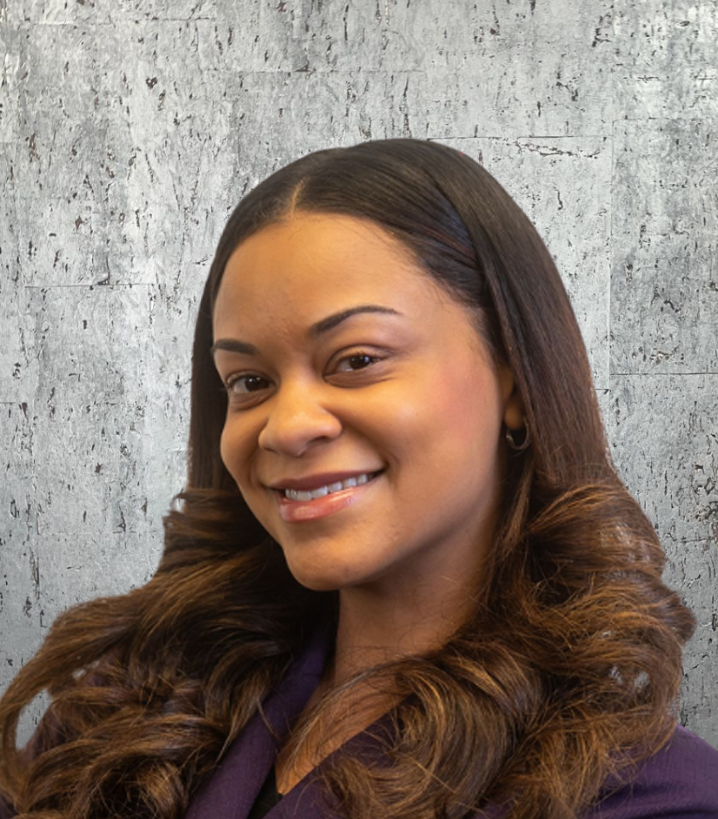 The woman is wearing a purple jacket and smiling for the camera.