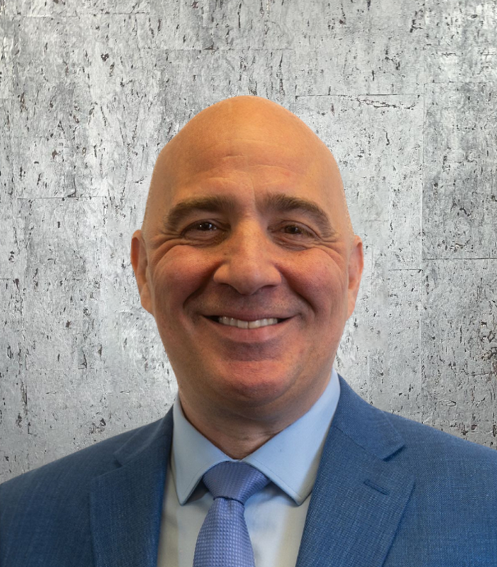 A bald man in a suit and tie is smiling for the camera.