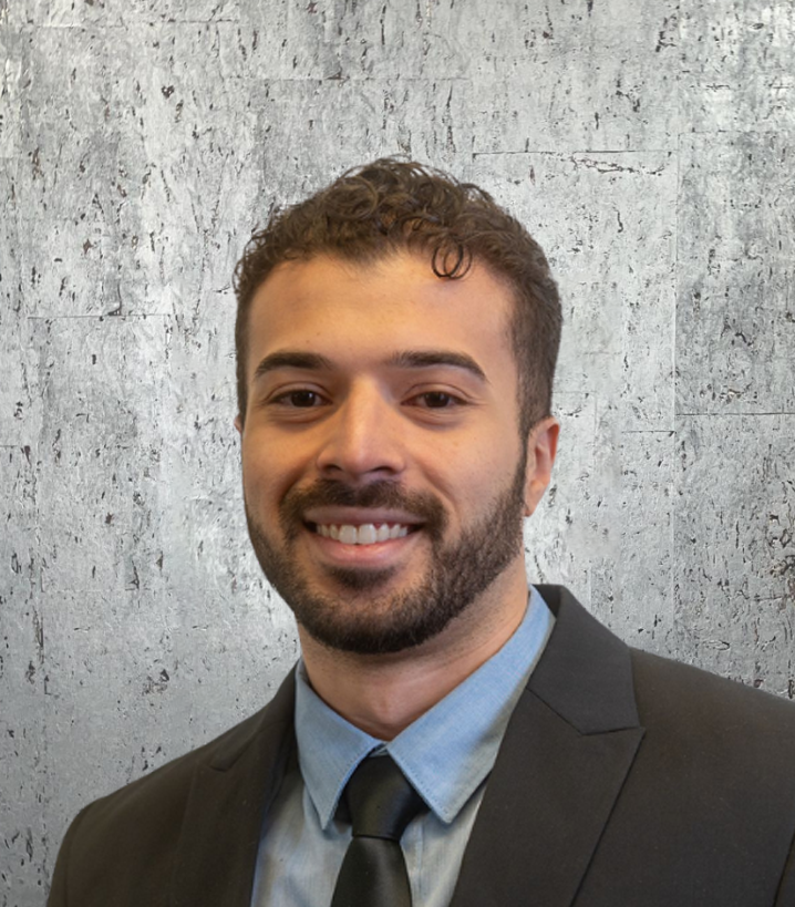 A man with a beard is wearing a suit and tie and smiling.