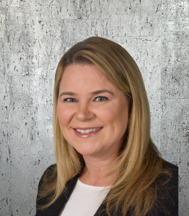 A woman is smiling in front of a concrete wall
