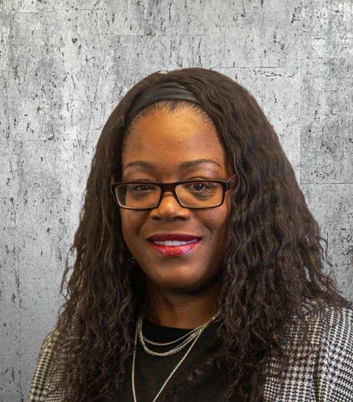 A woman wearing glasses and a headband is smiling for the camera.