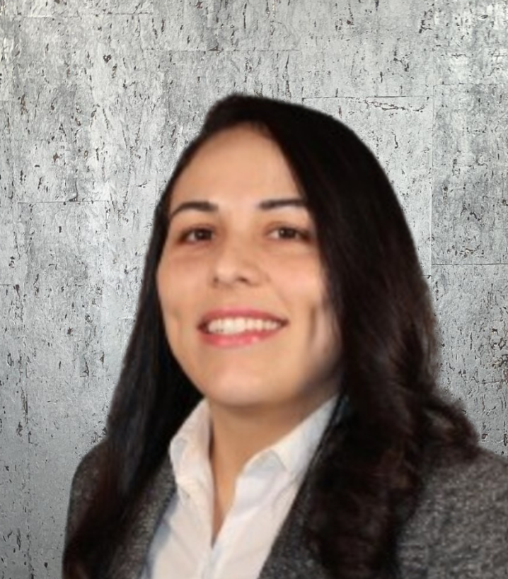 A woman in a grey jacket and white shirt smiles for the camera