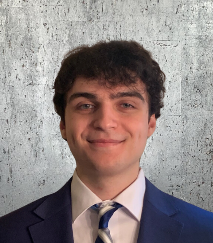 A young man in a suit and tie smiles for the camera