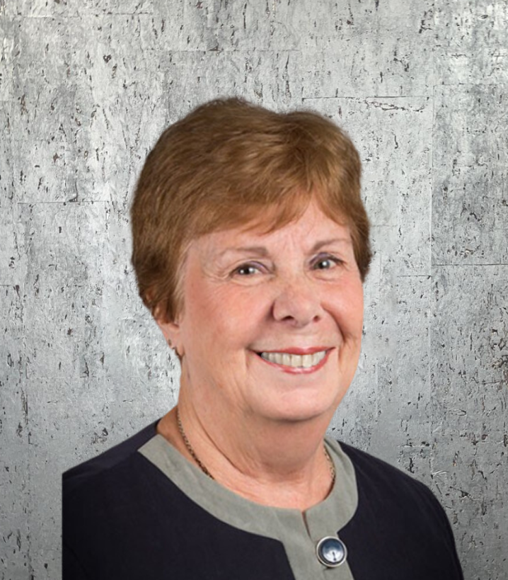 A woman is smiling in front of a concrete wall