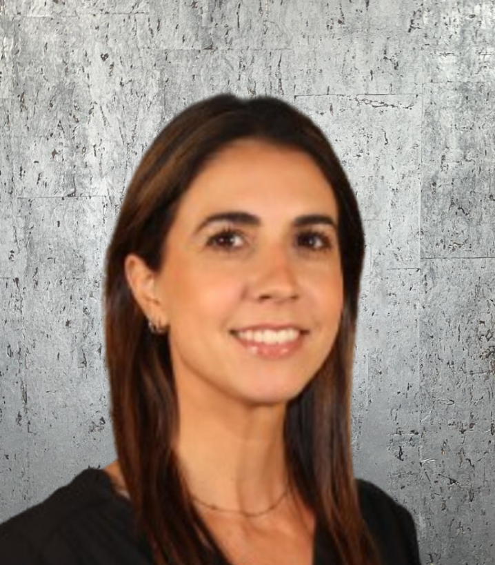 A woman in a black shirt is smiling in front of a gray wall