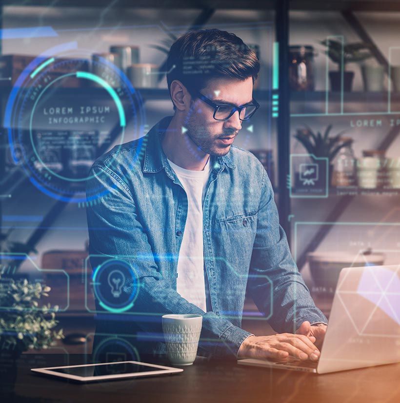 A man is sitting at a table using a laptop computer.